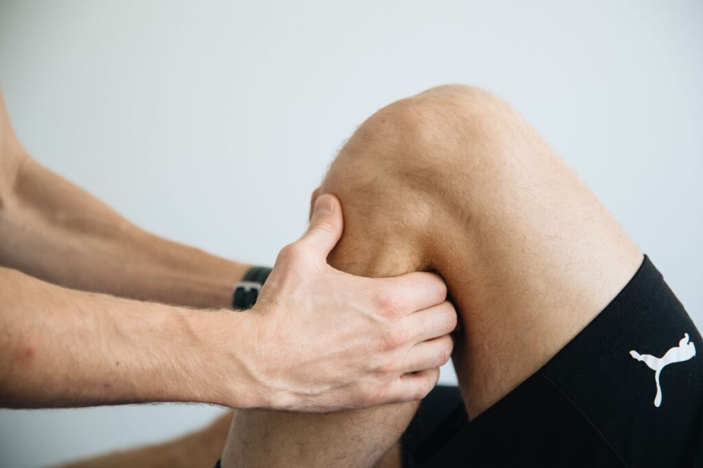 Therapist examining and treating patient knee during rehabilitation session